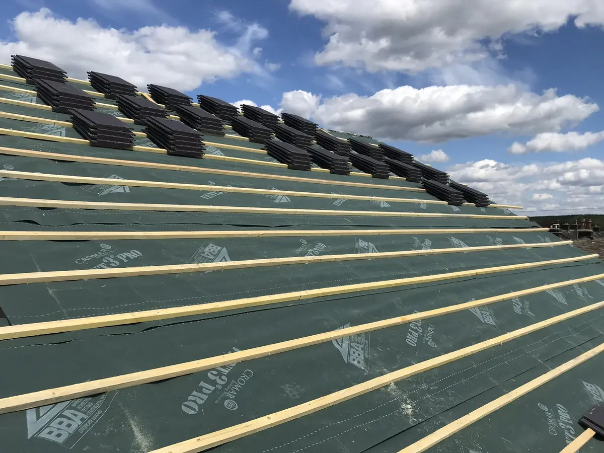 New roof tiles being laid on fresh battens and membrane